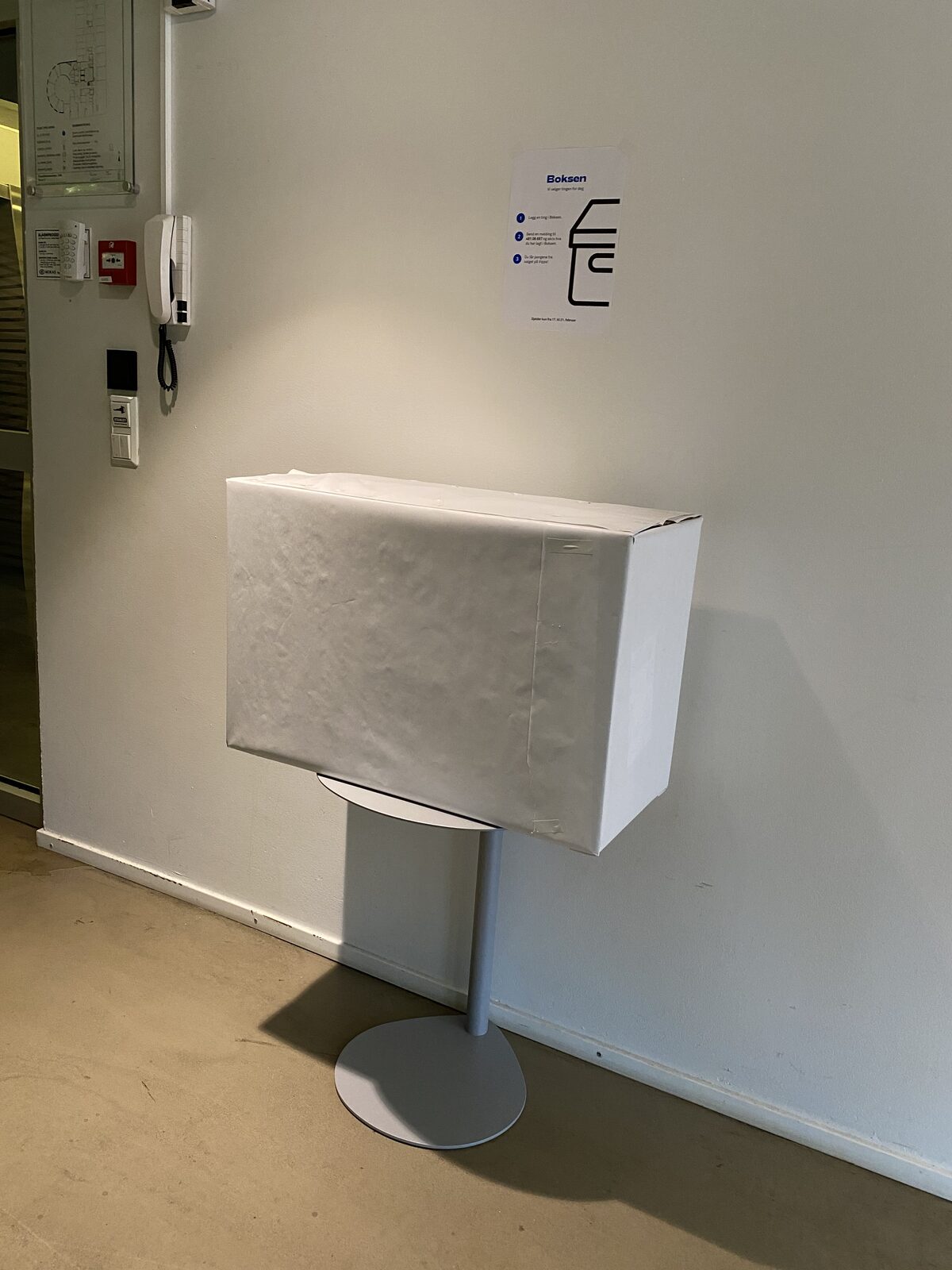 Tidlig hvit «Boksen»-prototype av Haralt-skapet montert på vegg med instruksjonsplakat